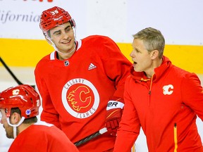 Matt Coronato smiles while skating and talking with Calgary Flames assistant coach Cail MacLean during the forward’s first practice with the team on Tuesday, March 28, 2023.