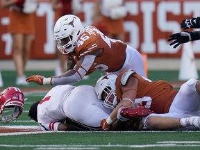 Louisiana-Lafayette quarterback Levi Lewis loses his helmet as he is sacked by Texas linebacker Ray Thornton (46) and safety Zach Edwards in Austin, Texas, on Sept. 4, 2021.