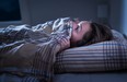 Scared woman hiding under blanket unable to sleep after nightmare.