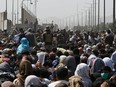 Afghans gather on a roadside near the military part of the airport in Kabul on Friday, Aug. 20, 2021, hoping to flee from the country after the Taliban's military takeover of Afghanistan.