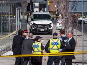 Police are seen near a damaged van in Toronto after a van mounted a sidewalk crashing into a number of pedestrians on Monday, April 23, 2018.