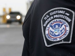 A U.S. Customs and Border Protection officer stands near a security booth as vehicles approach in Detroit, Mich, on Monday, June 1, 2009.
