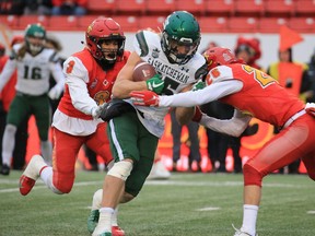 The Saskatchewan Huskies’ Jonathan Leggett is defended by the Calgary Dinos’ Jacob Biggs, left and Matthew Lucyshyn during the Hardy Cup at McMahon Stadium in Calgary on Nov. 9, 2019.