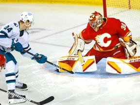 Calgary Flames goaltender Dustin Wolf defends the net as San Jose Sharks forward Jacob Peterson at the Scotiabank Saddledome in Calgary on Wednesday, April 12, 2023.