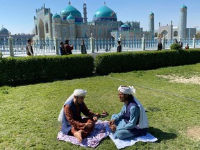 Afghan men sit in front of the Hazrat-e-Ali shrine or the blue mosque on the occasion of Nowruz, in Mazar-i-Sharif on March 21, 2023.