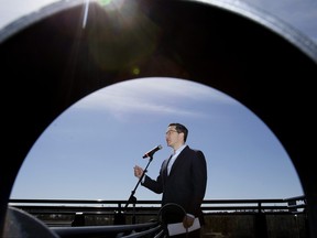 Pierre Poilievre, leader of the Conservative Party of Canada and the Official Opposition, is framed by the armrest of a park bench as he speaks to the media during a stop in Edmonton, Thursday April 13, 2023.