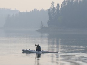 A paddler enjoys the morning calm on a smoky Glenmore Reservoir on Thursday, May 18, 2023.