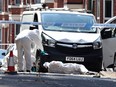 Police forensics officers work around a white van with a shattered windscreen, inside a police cordon on Bentinck Road in Nottingham, central England, following a 'major incident' in which three people were found dead.