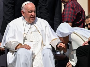 A nun kisses the hand of Pope Francis, seated in a wheelchair, at the end of the weekly general audience at St. Peter's square in The Vatican, Wednesday, June 7, 2023.