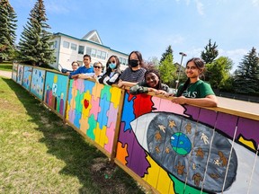 Heather Bryant, an elder at Westminster Presbyterian Church and Tom Baines School art teacher Lily Chow pose with some of the students who helped paint the Positivity Mural on the church's fence next door to the school.