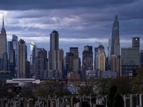 The sun sets behind the New York skyline, Sunday, Nov. 13, 2022, as seen from Calvary Cemetery.