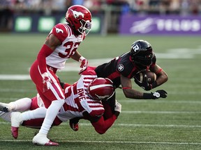 Ottawa Redblacks wide receiver Justin Hardy (2) is tackled by Calgary Stampeders linebacker Micah Awe (57) and defensive back Titus Wall (32) during first half CFL football action in Ottawa on Thursday, June 15, 2023.