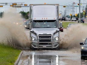 Vehicles run through a large puddle on 91 Street near 51 Avenue on Monday, June 19, 2023, in Edmonton. Environment Canada reported that 52.1 mm of rain fell at the Edmonton Blatchford weather station over 24 hours.