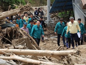 South Korea's President Yoon Suk Yeol (C) walks past piles of fallen trees at a village, where more than a third of houses were damaged in landslides and two people remain missing, in Yecheon on July 17, 2023.
