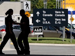 Canadian border guards are silhouetted as they replace each other at an inspection booth at the Douglas border crossing on the Canada-USA border in Surrey, B.C., on Thursday August 20, 2009.