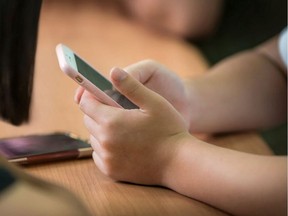 A child uses a smartphone at their desk.