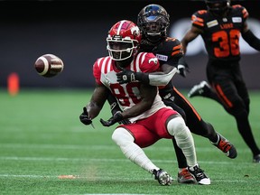 Calgary Stampeders' Marken Michel, front, makes the reception as he's hit by B.C. Lions' Emmanuel Rugamba during the first half of a CFL game in Vancouver on Saturday, August 12, 2023.