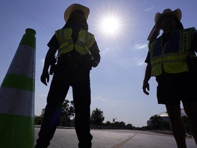 The sun beats down as police officers stand by to direct pedestrians after a sporting event in Arlington, Texas, on Sunday, Aug. 20, 2023.