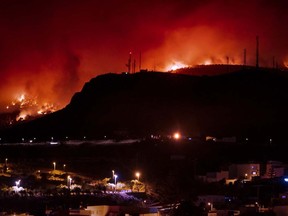 In this picture taken from the village of Sobradillo, late on August 16, 2023, a wildfire rages in a forested area on the Canary island of Tenerife