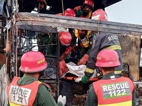 This handout photograph taken and released by Pakistan's Emergency Rescue 1122 Service on August 20, 2023 shows rescue workers carrying a victim's body from a burned passenger bus at the site after a accident on a highway near the town of Pindi Bhattian in eastern Punjab province. At least 18 people burned to death on August 20 when an overnight bus smashed into another vehicle carrying diesel in eastern Pakistan, officials said.