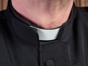 Closeup of the neck of a priest wearing a white clerical collar.