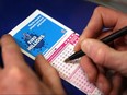 A punter fills out a National Lottery ticket on February 7, 2008 in London.