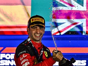 Ferrari's Spanish driver Carlos Sainz Jr sprays champagne as he celebrates on the podium after winning the Singapore Formula One Grand Prix night race at the Marina Bay Street Circuit in Singapore on Sept. 17, 2023.