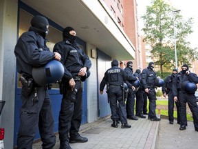 Police officers on duty during a raid stand in front of an apartment building in Stade, Germany, Tuesday Sept. 26, 2023.
