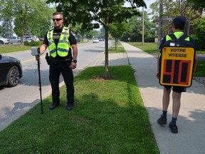 A Montreal police officer stands by as a child with a backpack, equipped with a readout showing drivers' speeds, in a Friday, June 30, 2023, handout photo.
