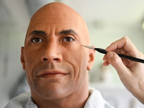 A painter works on updating a wax figure of Dwayne Johnson at the Grévin Museum in Paris.
