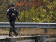 A police officer walks along a rural road during a manhunt for the suspect of Wednesday's mass shootings, Thursday, Oct. 26, 2023, in Lisbon, Maine. The shootings took place at a restaurant and bowling alley in nearby Lewiston, Maine.