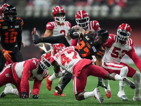 B.C. Lions' JaQuan Hardy is hit by Calgary Stampeders' Brad Muhammad as he carries the ball during the first half of game in Vancouver
