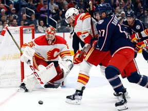 Calgary Flames goalie Jacob Markstrom, left, makes a stop in front of Flames defenseman Chris Tanev, center, and Columbus Blue Jackets forward Justin Danforth during the second period of an NHL hockey game in Columbus, Ohio.