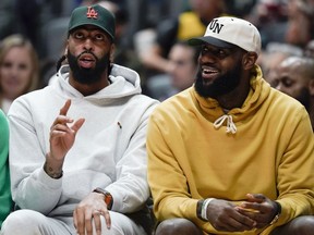 Los Angeles Lakers forwards Anthony Davis, left, and LeBron James watch from the bench during the first half of the team's preseason NBA basketball game against the Sacramento Kings on Wednesday, Oct. 11, 2023, in Anaheim, Calif.