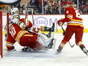 William Carrier #28 of the Vegas Golden Knights collides with Dan Vladar #80 and Chris Tanev #8 of the Calgary Flames during the first period at the Scotiabank Saddledome on November 27, 2023 in Calgary, Alberta, Canada.