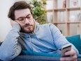 Single lonesome man checking mobile phone on the couch