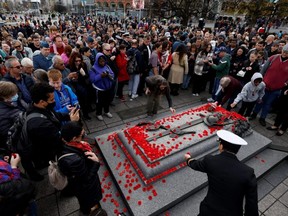 People lay poppies on the Tomb of the Unknown Soldier following the Remembrance Day ceremony at the National War Memorial in Ottawa, Friday, Nov. 11, 2022.