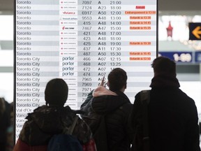 Passengers look at an information board at the departures terminal at Pierre Elliott Trudeau Airport in Montreal, Tuesday, Dec. 31, 2019.