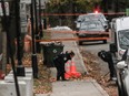 Police officers look through leaves in front of Yeshiva Gedola school on Deacon Road in the in the Notre-Dame-de-Grâce—Côte-des-Neiges borough of Montreal Sunday, November 12, 2023 where gunshots were fired early Sunday morning.