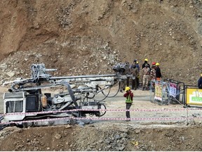 Rescuers stand near heavy machinery at the site of an under-construction road tunnel that collapsed in mountainous Uttarakhand state, India, Friday, Nov. 17, 2023.