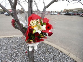 Flowers and a teddy bear are tied to a tree on Wednesday near the scene of Monday's fatal shooting at the TransCanada Centre mall in northeast Calgary.