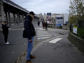 People look at a blood stain on the scene where a man targeted passersbys Saturday, killing a German tourist with a knife and injuring two others in Paris, Sunday, Dec. 3, 2023.