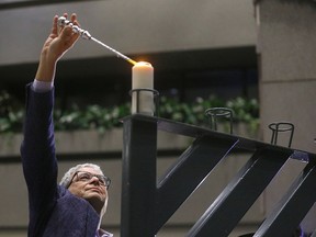 Nelson Halpern lights the second candle on the menorah during a ceremony at Calgary city hall on Thursday.