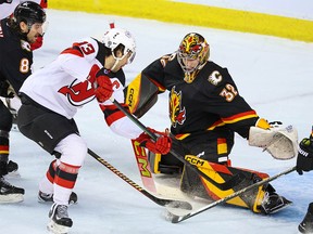 Calgary Flames goaltender Dustin Wolf stops this scoring chance by New Jersey Devils forward Nico Hischier during NHL action in Calgary on Saturday, December 9, 2023.