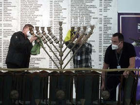 Workers in the Polish parliament clean up a menorah after a far-right lawmaker grabbed a fire extinguisher and put out a candle in Warsaw, Poland, on Tuesday Dec. 12, 2023.