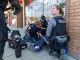 Members of the community safety team help a drug poisoning victim in Chinatown on June 22, 2023, in Edmonton.