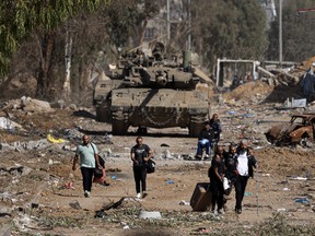Palestinians fleeing the north through the Salaheddine road in the Zeitoun district on the southern outskirts of Gaza City, walk past Israeli tanks.