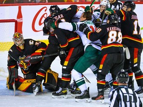 Flames and Wild players fighting around goalie Dustin Wolf