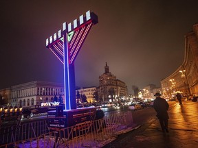 A man walks past menorah after lighting candles marking the fifth night of the Jewish holiday of Hanukkah on Independence square in Kyiv, Ukraine, Monday, Dec. 11, 2023.