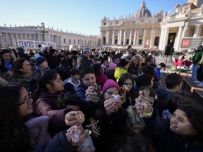 Children hold up statues of baby Jesus as they wait for Pope Francis' Angelus noon prayer he celebrates from the window of his studio overlooking St.Peter's Square, at the Vatican, Sunday, Dec. 17, 2023.